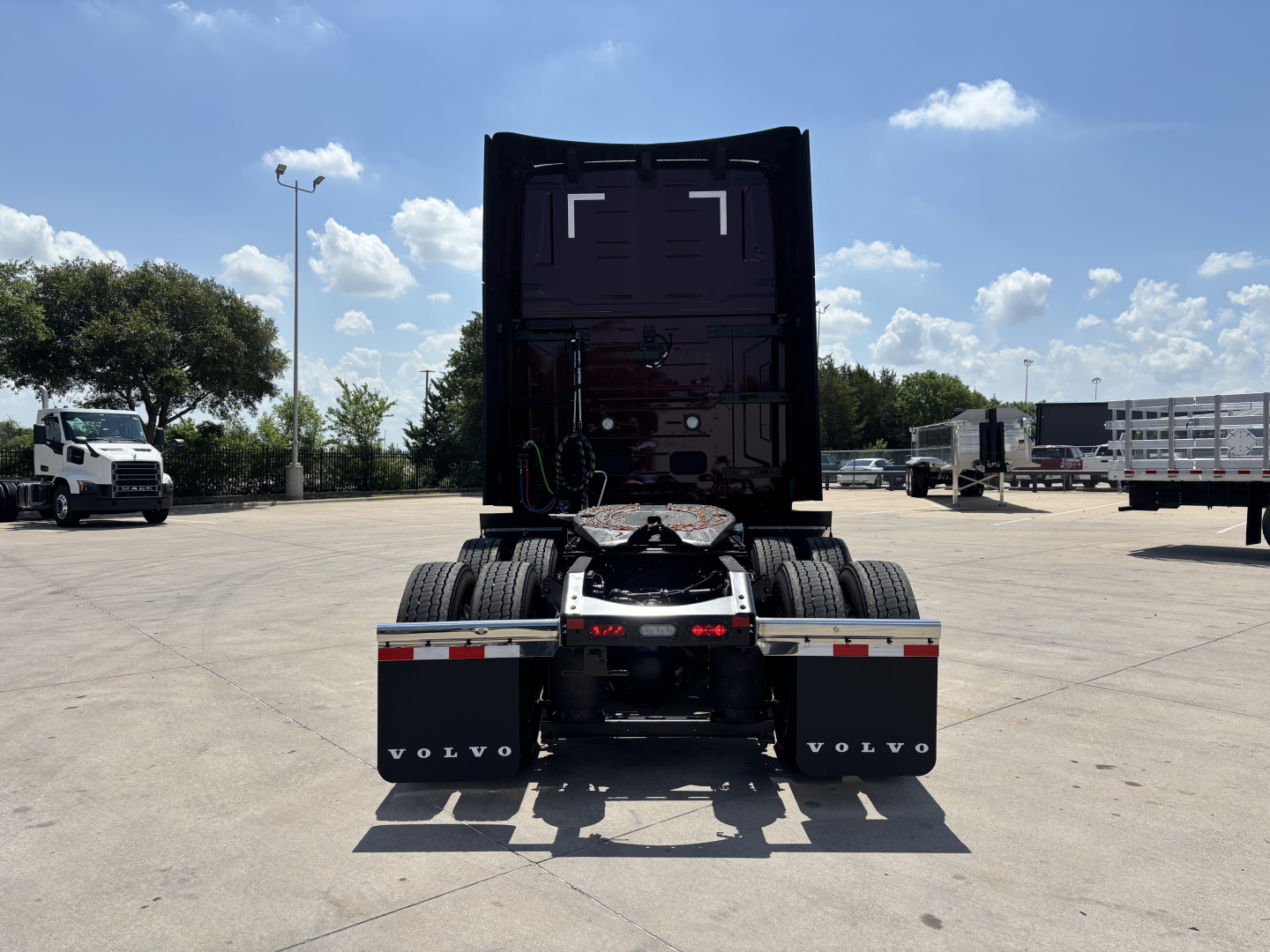 Volvo VNL64T860 tractor rear view showing fifth wheel and dual rear axles with plastic mudflaps labeled VOLVO.