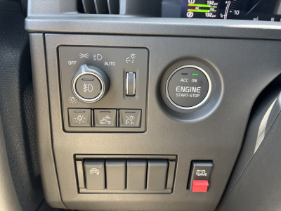 Volvo VNL64T860 dashboard with ignition engine start-stop button and lighting controls panel showing circular knob, switches, and red hazard button.