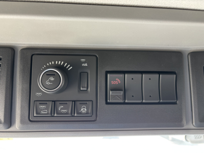 Truck dashboard panel showing climate control dial, several indicator buttons, and a row of blank switches.