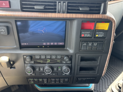 Volvo VNL64T860 truck interior showing dashboard with touchscreen, climate controls, and yellow/red warning buttons.