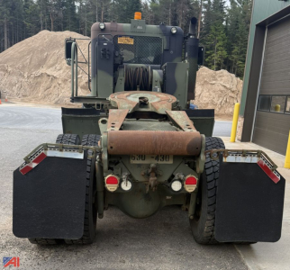 M916A3 tractor rear view showing heavy-duty hitch, dual rear wheels, mud flaps, and two red tail lights with white reflectors.