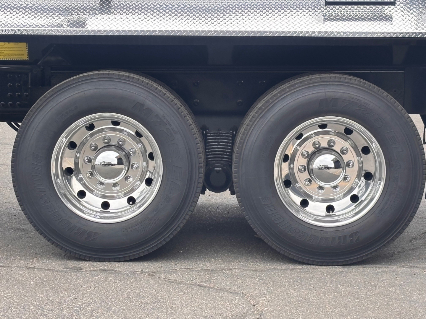 Mack PI64 truck dual rear wheels showing polished chrome rims and tires with black rear suspension and undercarriage