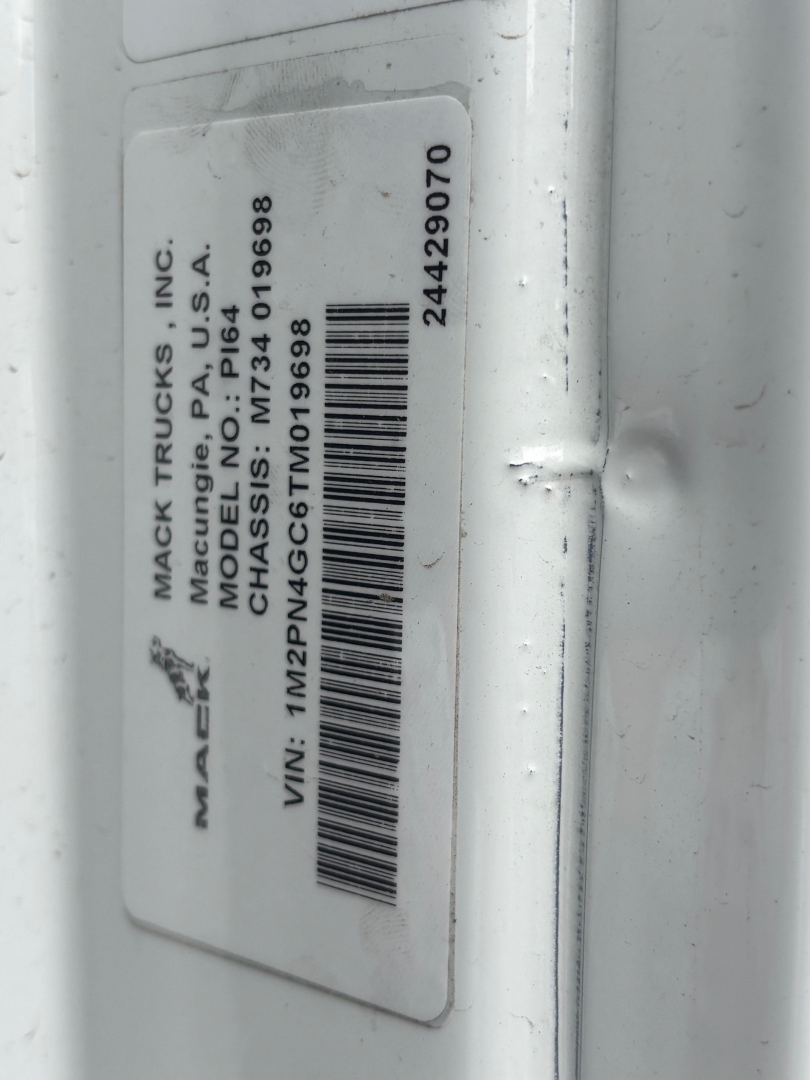 Mack Trucks label showing model, VIN, and serial numbers on a white surface; vertical orientation with barcode. Text includes 'MACK TRUCKS INC', 'MODEL DUMP', 'MODEL PI64', 'VIN: 1M2PN4GC6TM019698', 'STOCK: 70571', '187? 344-...'