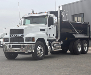 Mack PI64 dump truck in white with black dump body, front grille shows 'MACK' emblem, chrome bumper, dual rear axles.