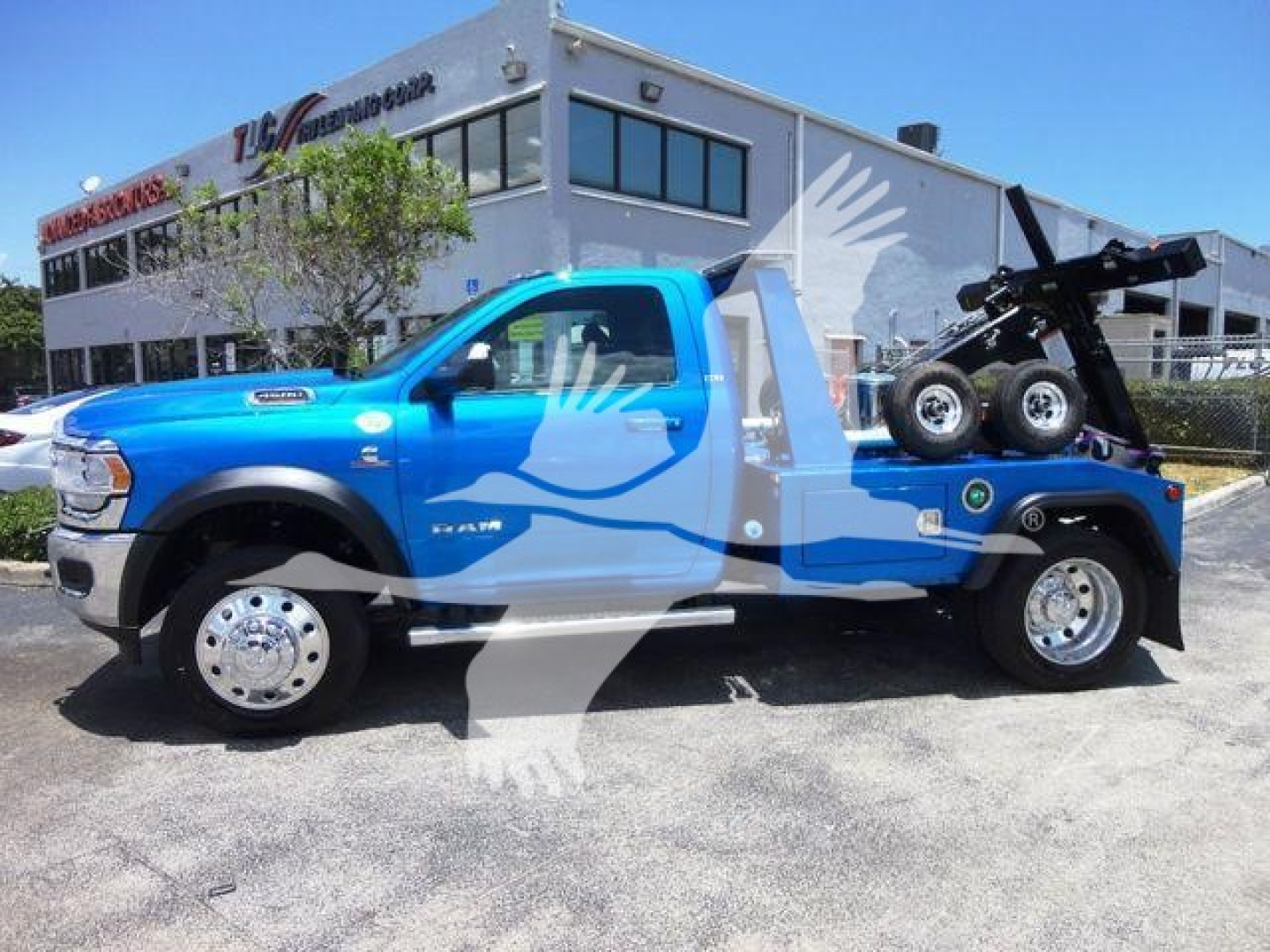 2025 Ram 4500 SLT pickup truck in blue with a tow winch bed, parked outside a dealership.
