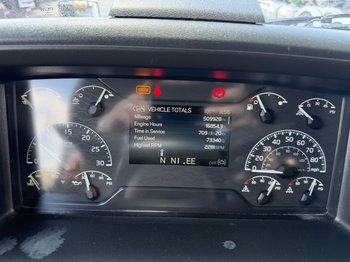 Instrument cluster and digital display on a Volvo VNL truck dashboard showing vehicle totals: engine hours, time in service, fuel used, highest RPM, and RPM readouts.