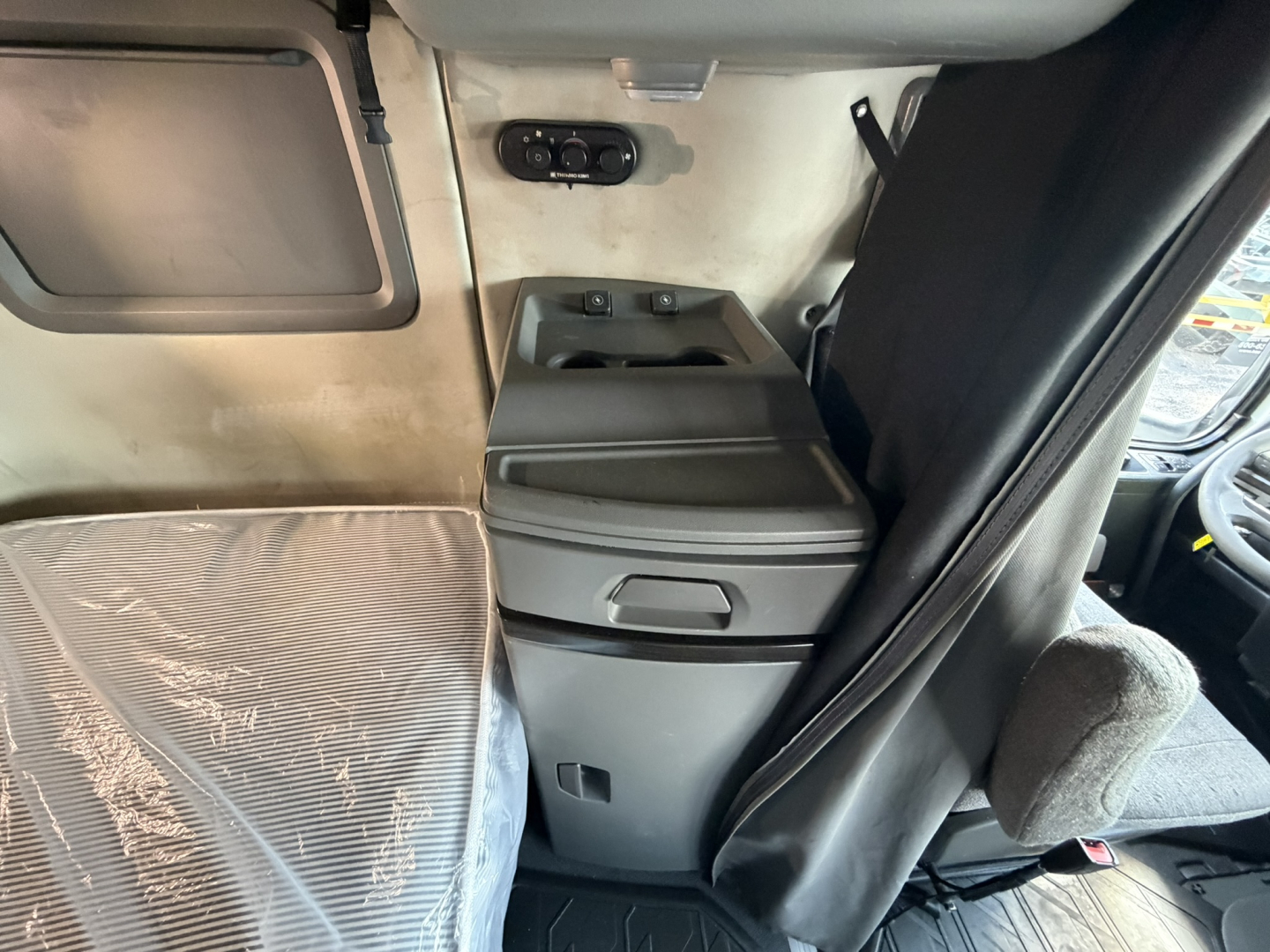 Volvo VNL64T740 sleeper cab interior showing center console and driver seat area with windows and storage compartments.