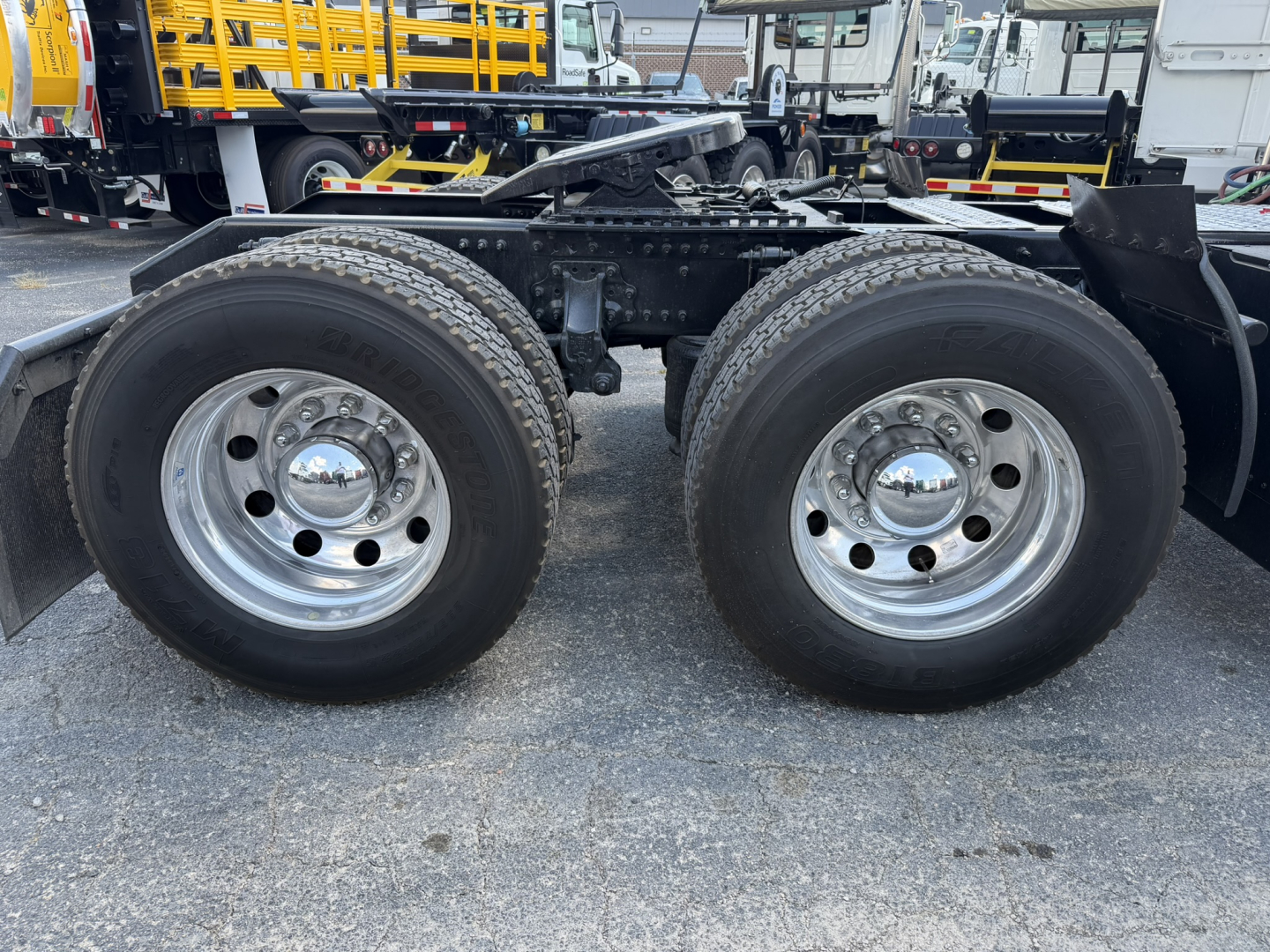 Volvo VNL truck rear dual wheels showing chrome hubcaps and tire treads with frame and fifth wheel visible.