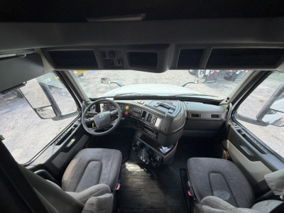 Truck cab interior of a 2021 Volvo VNL64T740 with L-seat dashboard, steering wheel, and driver/passenger seats visible.