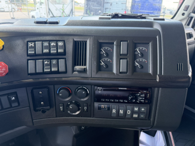 Volvo VNL64T740 truck dashboard cockpit with several gauges, controls, and a radio, showing climate controls and gear selector with R N D M positions.