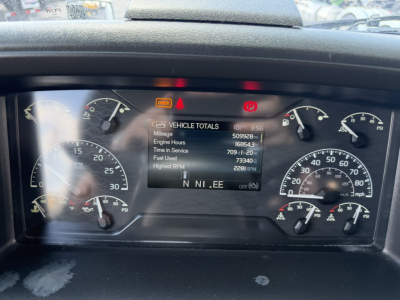 Instrument cluster and digital display on a Volvo VNL truck dashboard showing vehicle totals: engine hours, time in service, fuel used, highest RPM, and RPM readouts.