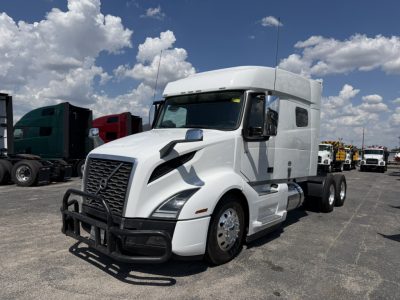 Volvo VNL64T740 sleeper tractor in white, front grille with bumper guard, two fuel tanks, triple rear axles, chrome wheels, side mirrors, and aerodynamic design.