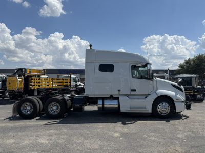 Volvo VNL64T740 truck side view showing sleeper cab, two rear axles, and chrome wheels.