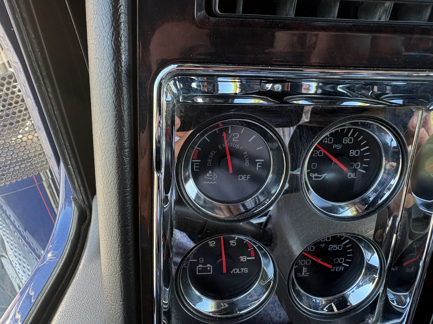 Kenworth W900L dashboard gauges showing DEF/engine coolant, RPM, oil pressure, and air pressure in chrome-trimmed cluster.