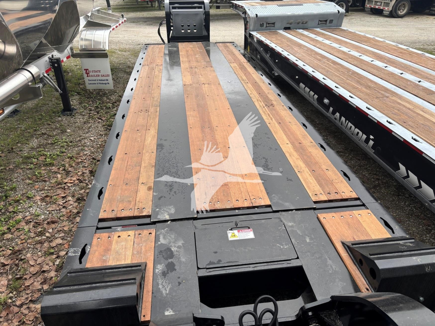 Flatbed trailer deck with wooden planks and steel beams; center access hatch and black frame; Fontaine 55MX trailer features visible in image