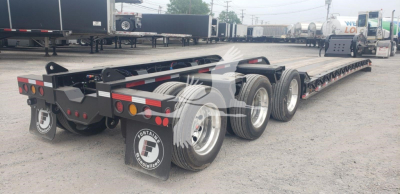 Flatbed trailer showing triple-axle rear and long lowboy deck with wheels and mud flaps; Fontaine logo visible on mud flap and reflective markings along the sides.