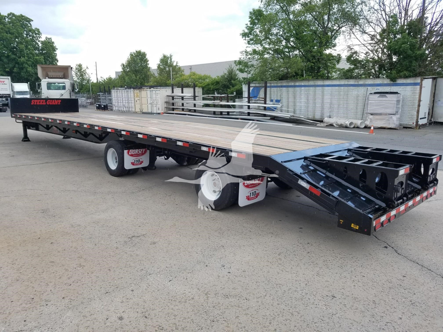 Beavertail dropdeck trailer showing long flatbed, tandem axles, black chassis, and steel construction with platform and ramps.