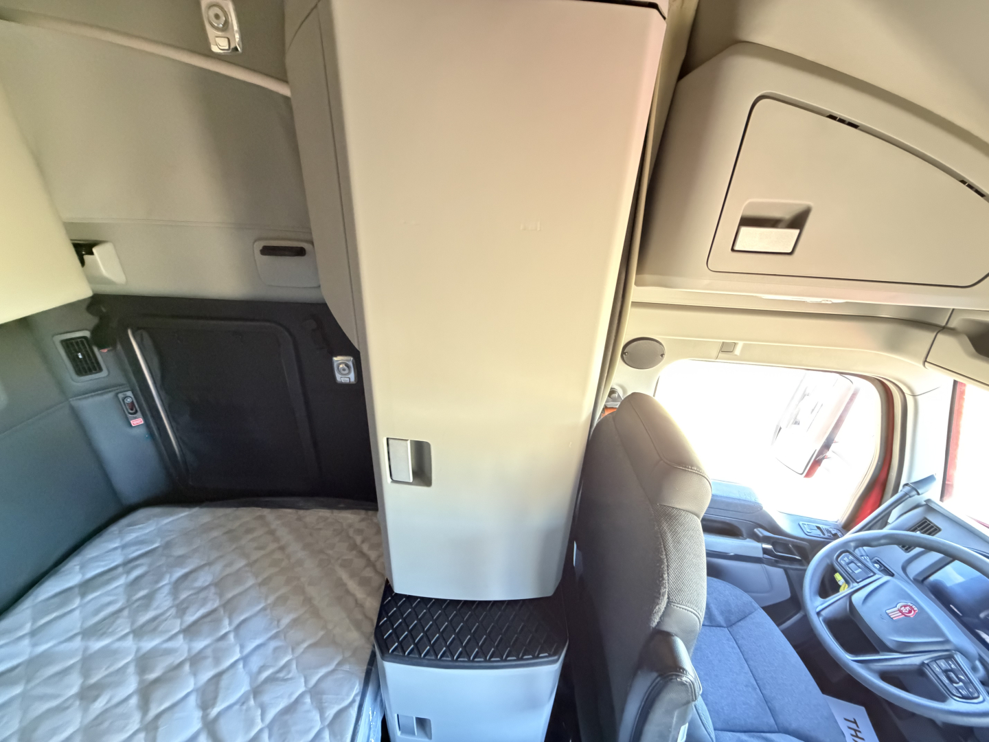 Kenworth T680 cabin interior with sleeper area and center console, driver seat, and dashboard visible.