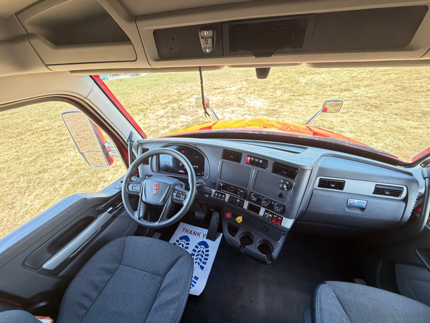 Kenworth T680 interior dashboard and steering wheel view from driver's seat showing center console, gauges, and controls.