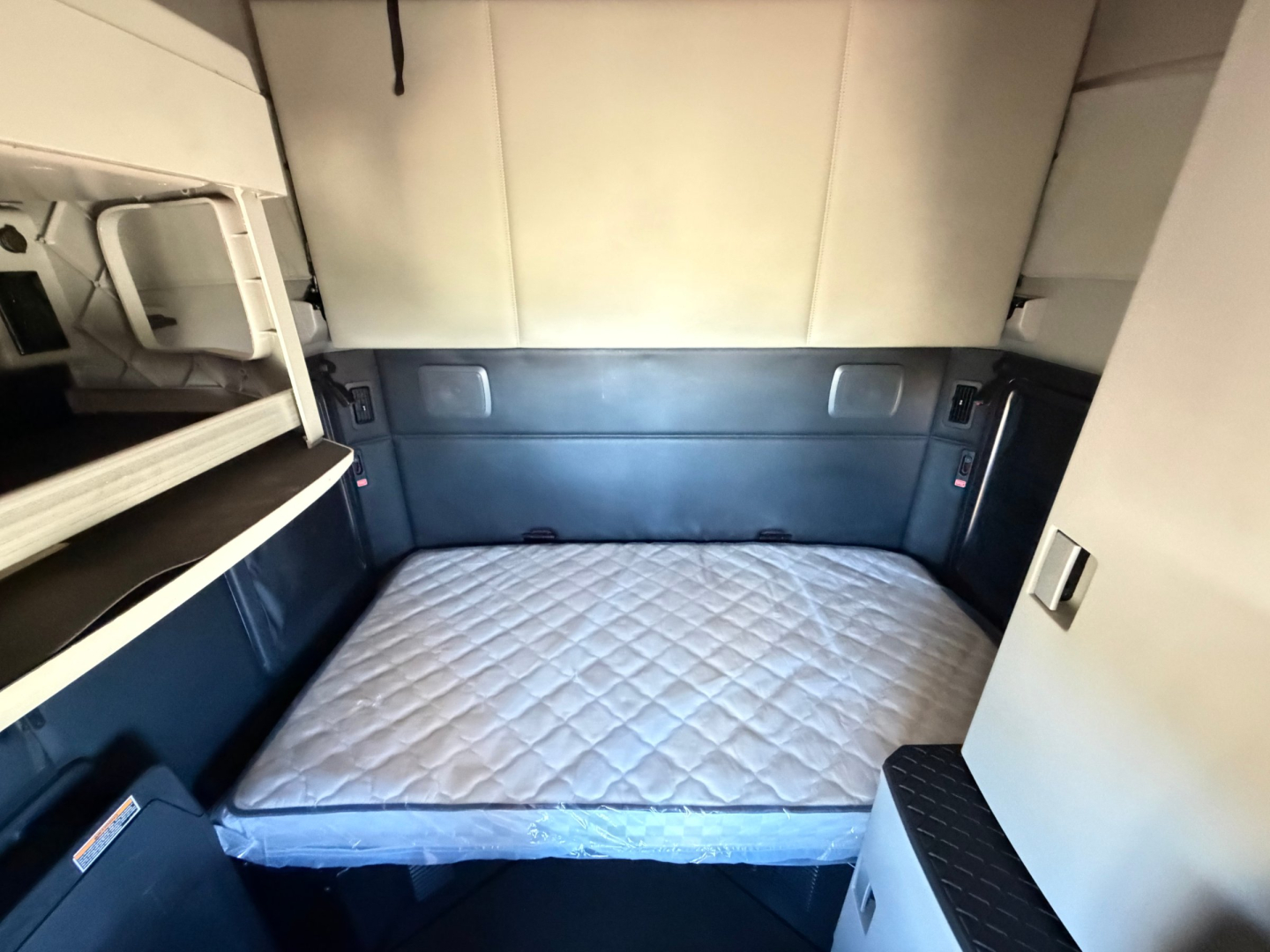 Kenworth T680 sleeper cab interior with bed mattress and side panels visible.