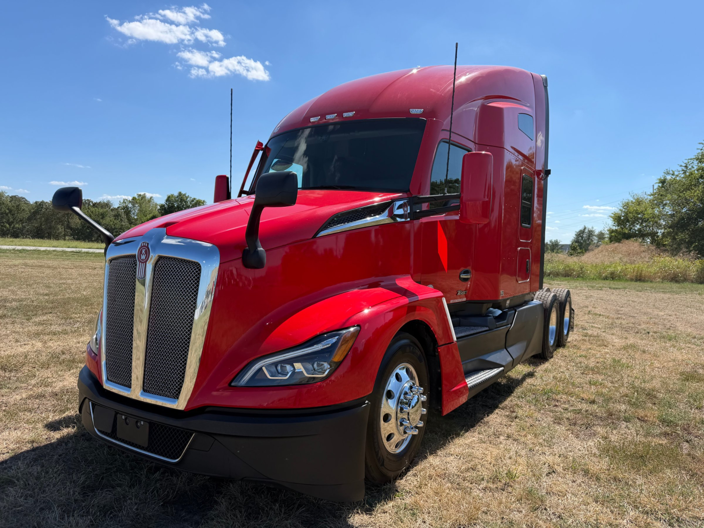 Kenworth T680 semi-truck in red exterior, front-left angled view showing chrome grille, dual side mirrors, and sleeper cab, no visible text on components.