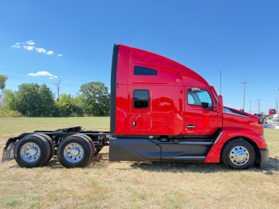 Red Kenworth T680 sleeper cab tractor side view showing side panel and rear axles, clear sky, no visible model text or numbers unreadable.