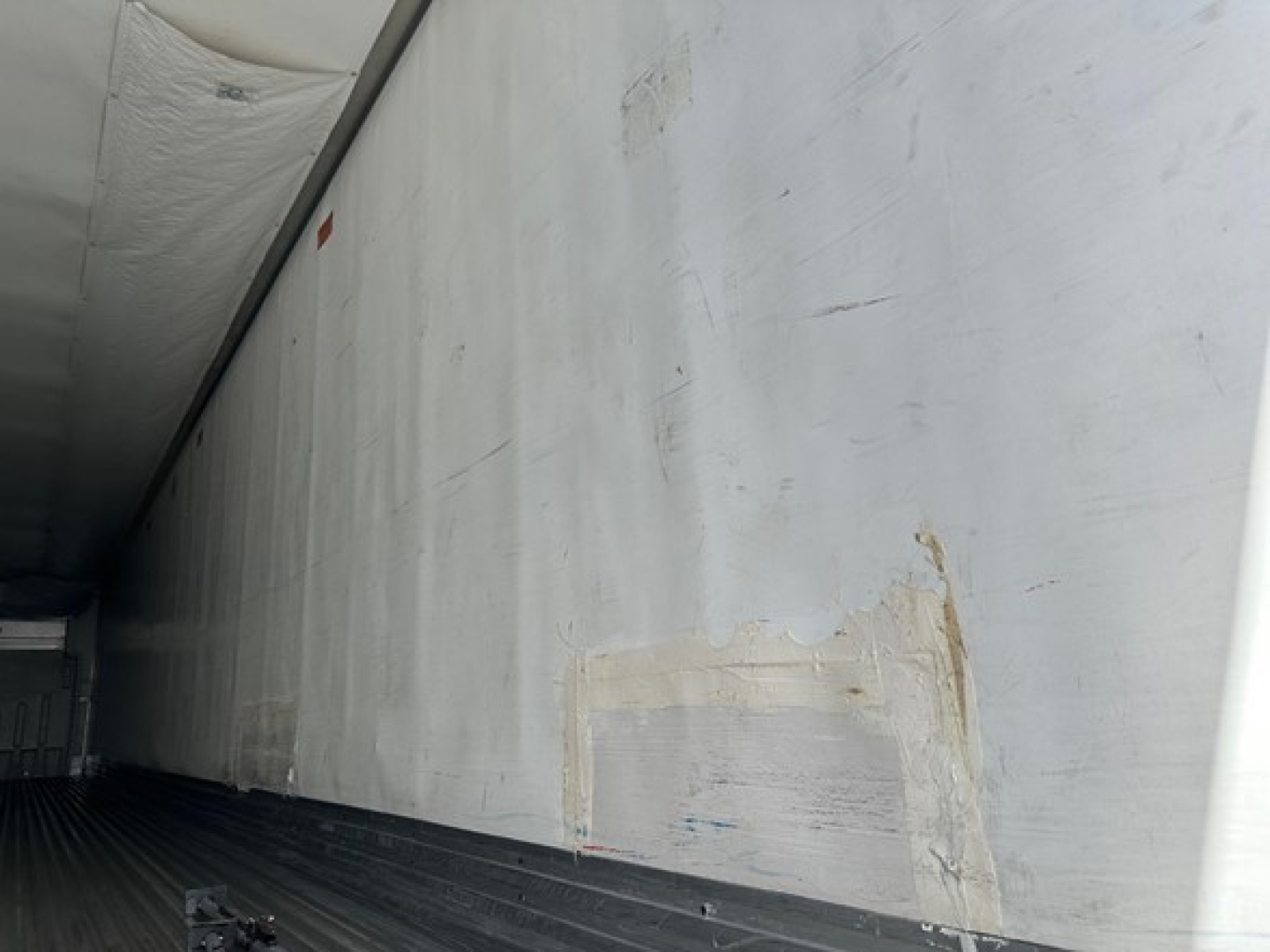 Trailer interior wall with scuff patches and a faded rectangular repair on the aluminum surface.