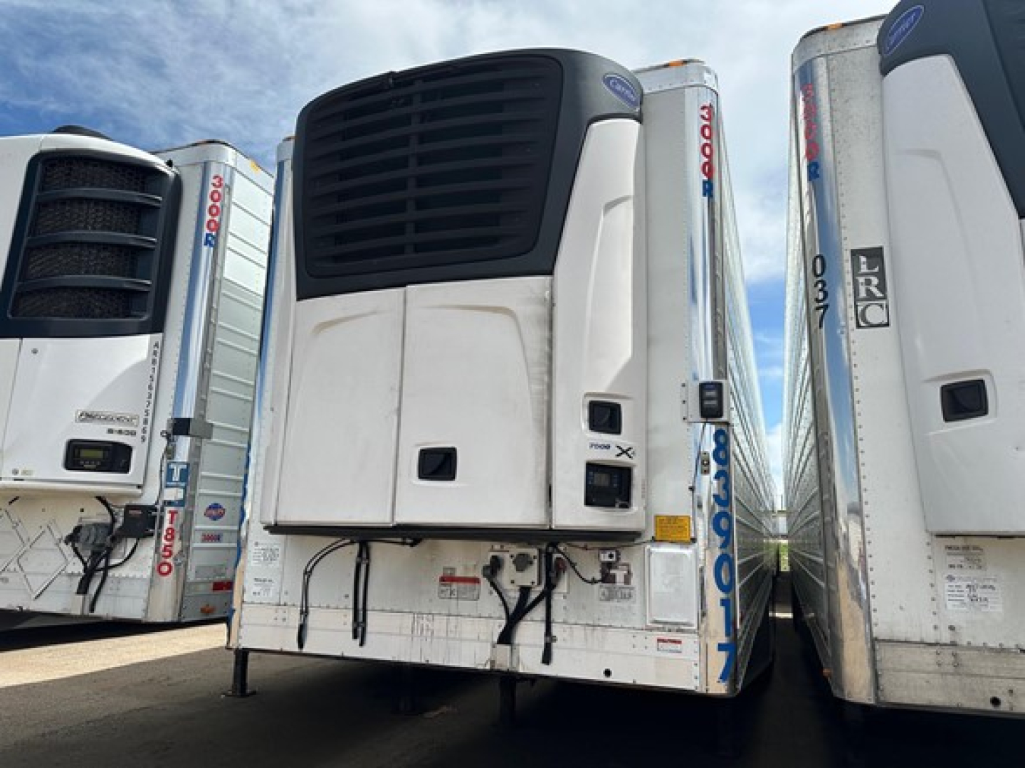 Unit showing a Utility 3000R refrigerated trailer with upright black vent on front, white refrigerated unit, side gates, and blue sky. Visible labels and serials include UE10818 and 2018 model.