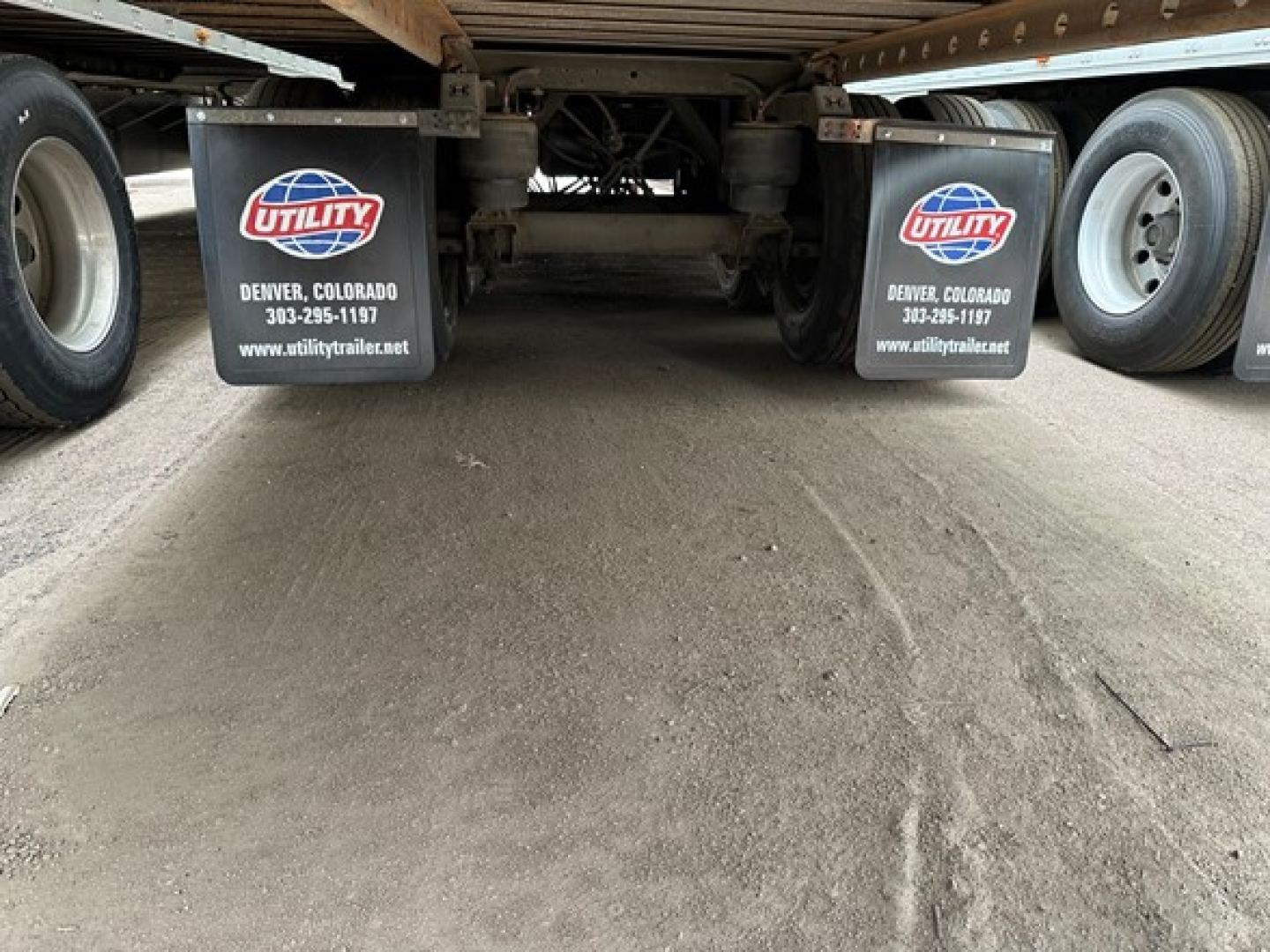 Rear view of a Utility air-ride trailer showing mud flaps with Utility logo and Denver, Colorado contact info, undercarriage and wheels.