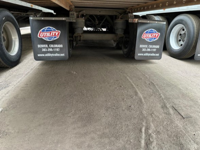 Rear view of a Utility air-ride trailer showing mud flaps with Utility logo and Denver, Colorado contact info, undercarriage and wheels.