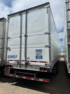 Trailer rear view showing Utility air ride 3000R refrigeration trailer with doors closed, CAUTION wide turns sticker, blue 839017 number, license plate area, rear lights.