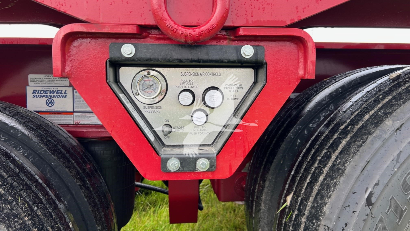Trailer hitch area of a Fontaine lowboy trailer showing suspension diagnostic panel and dual rear wheels.