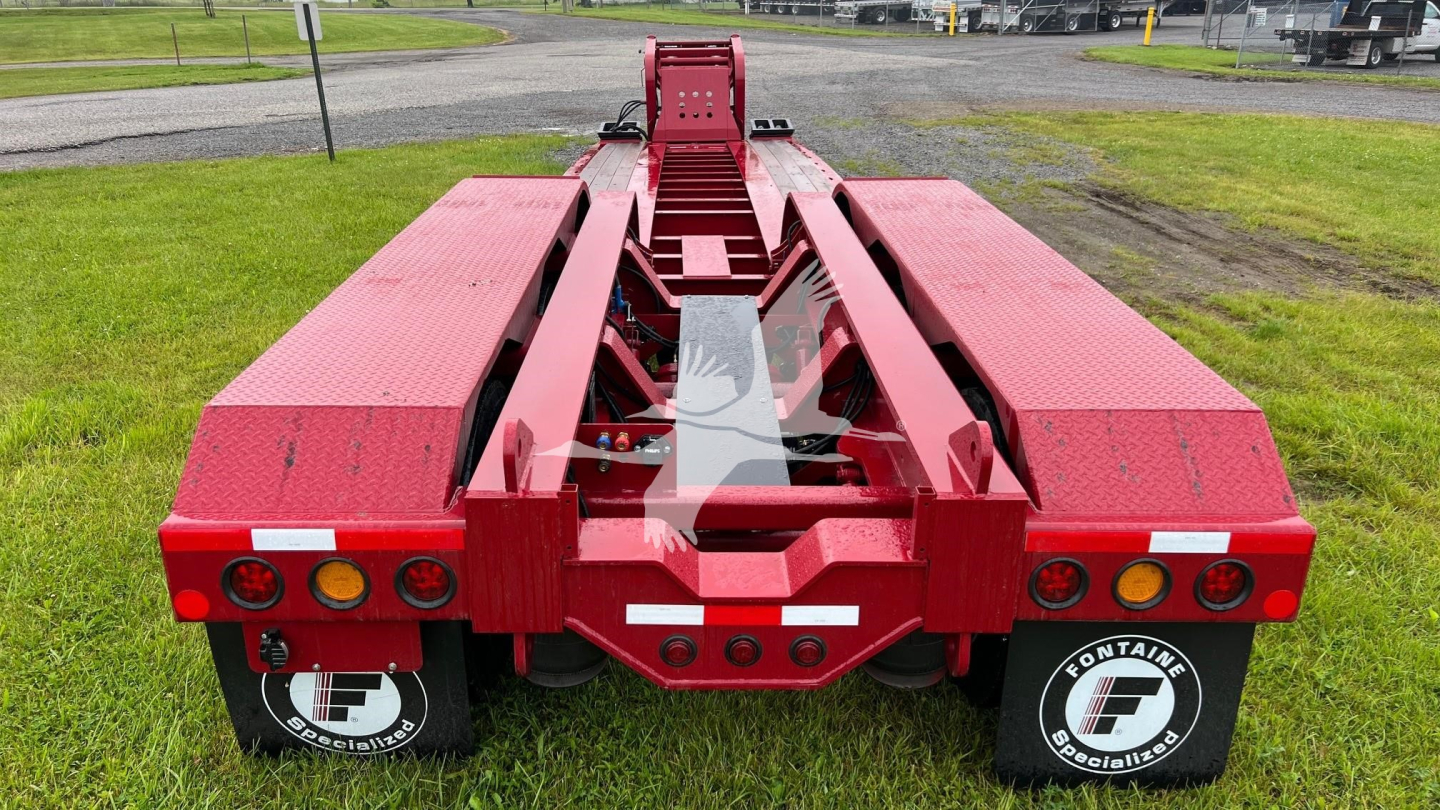 Red Fontaine lowboy trailer rear view showing deck and undercarriage with taillights and ramps; Fontaine branding on mudflaps.