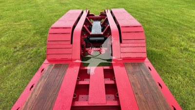 Lowboy trailer deck with red frame showing wooden planks and coupling area.