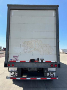 Rear view of a 2016 Wabash van trailer with a white door, red and white reflective tape, and bumper lights.