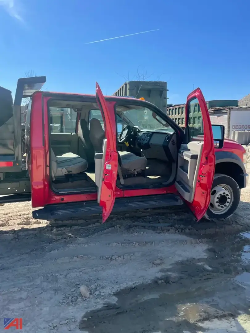 Truck cab with all four doors open; red Ford F-550 crew cab; interior dashboard and seats visible; side profile shows dump truck body in yard.