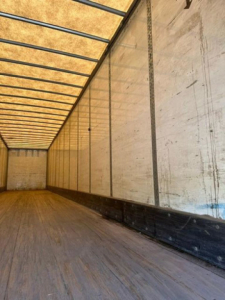 Interior view of a 2014 Wabash van trailer with wooden floor, metal ribs, and white side walls.
