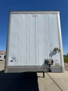 Trailer rear view showing aluminum box with riveted panels, rear bumper, hitch, and safety latches on a Wabash van trailer.