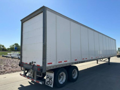 Trailer side view showing tandem axle semi-trailer with white aluminum walls and reflective red/white stripes.