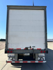 Trailer rear view of a used 2014 Wabash van trailer showing tail lights, bumper, and UK license plate with U.S. state stickers.