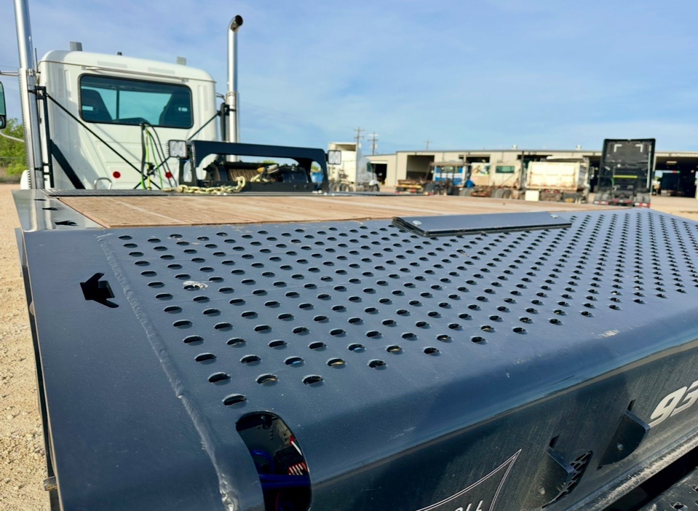 Docking perforated metal deck of Landoll 930E-51-15 trailer with perforated steel surface and a partial side view, blue color, industrial yard in background.