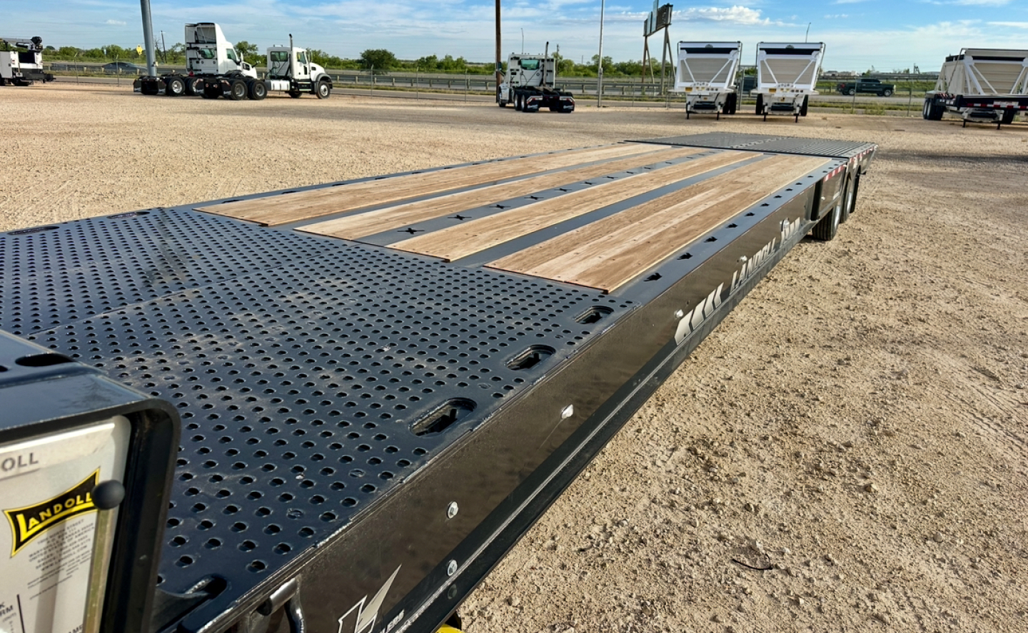 Landoll 930E-51-15 trailer deck view showing perforated steel gooseneck and wooden planks with wheel wells along side.