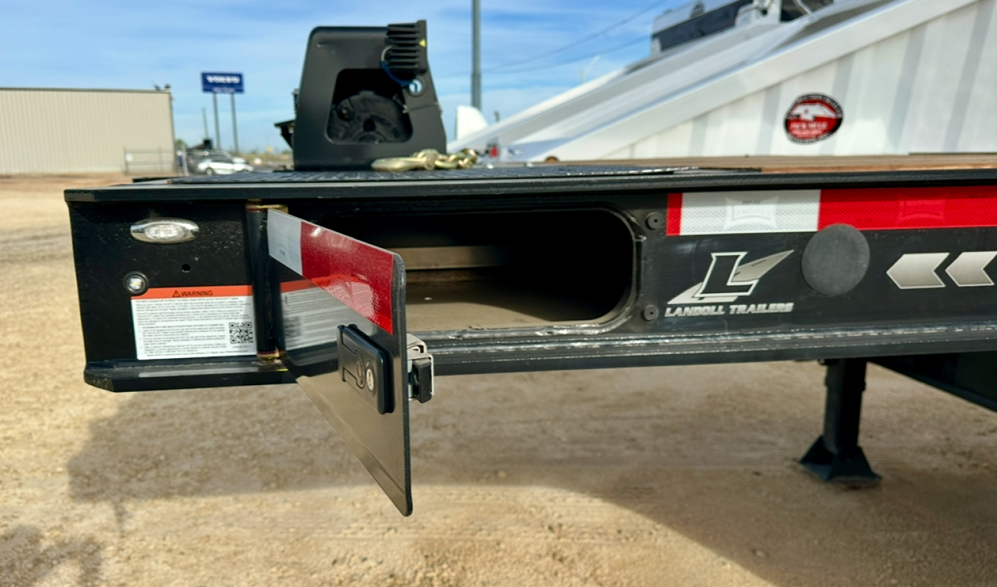 Trailer rear with fold-down ramp and branding showing Landoll logo and metal frame, side toolbox door open.