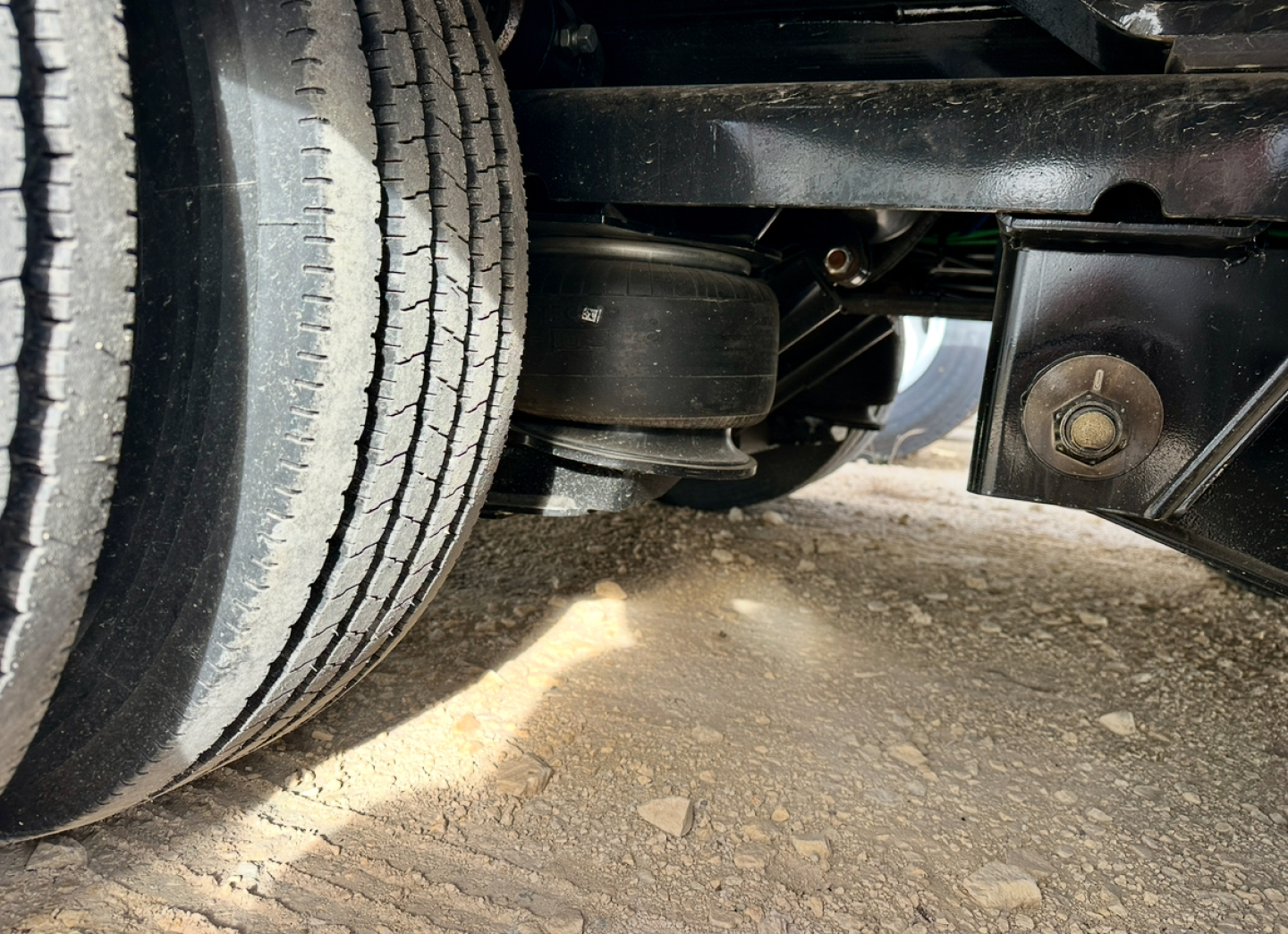 Trailer undercarriage with dual tires and air spring suspension showing frame and mounting hardware.