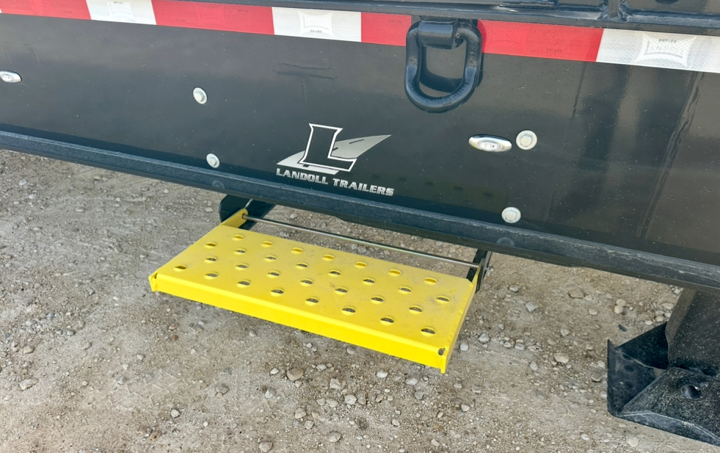 Trailer rear showing Landoll Trailers logo and yellow perforated step beneath tailgate.