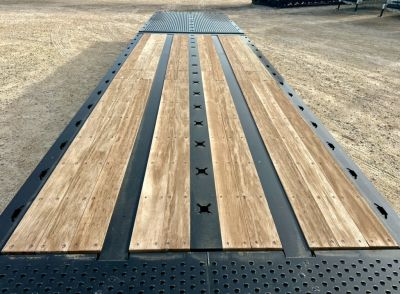 Landoll trailer deck showing wooden planks with black steel center rails and perforated edge; top deck plate visible in distance.