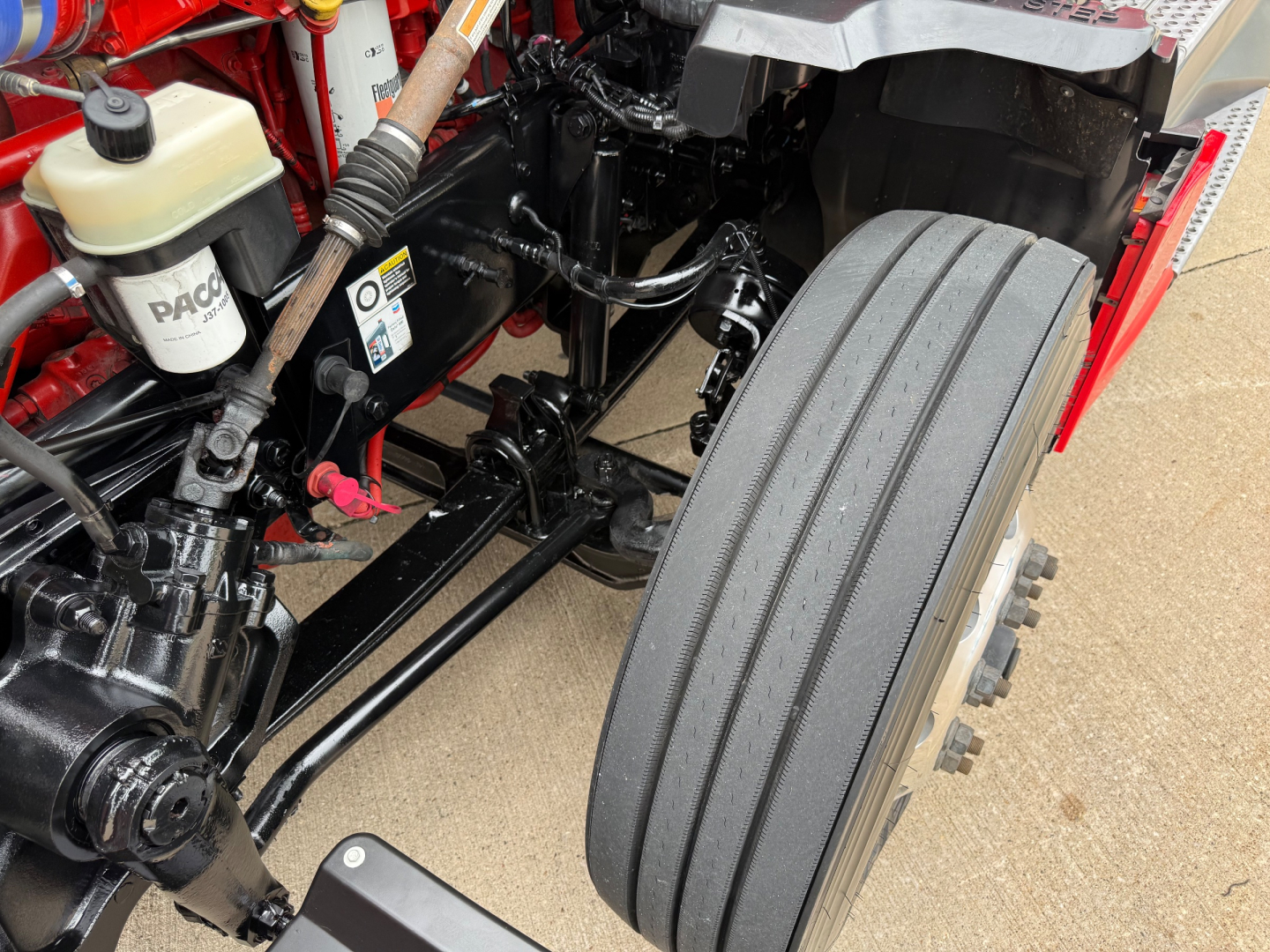 Kenworth T680 engine bay and front suspension showing air filter reservoir and dual rear tandem wheel area.