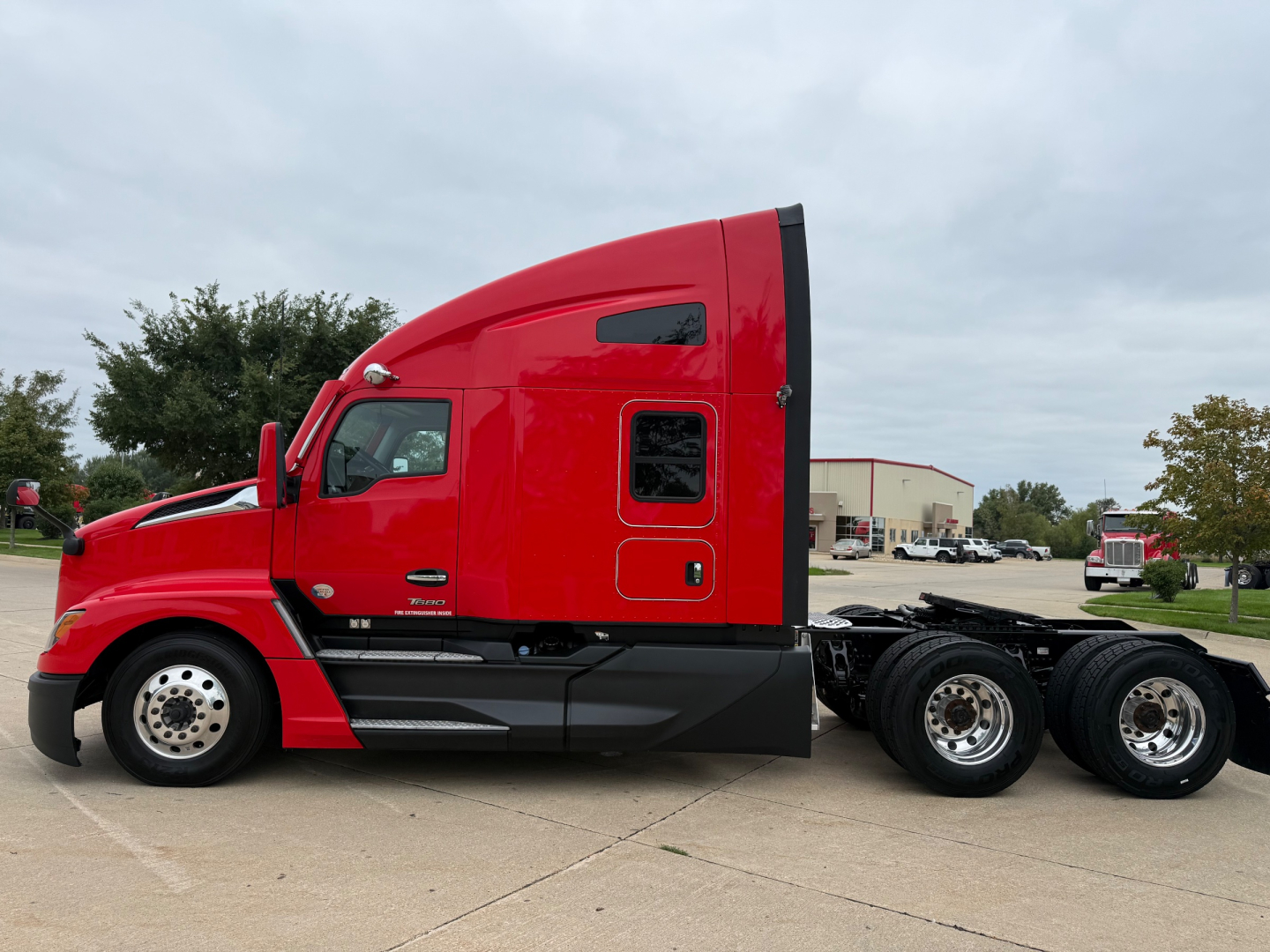 Kenworth T680 truck side view showing sleeper cab and attached chassis with red paint and black lower trim.