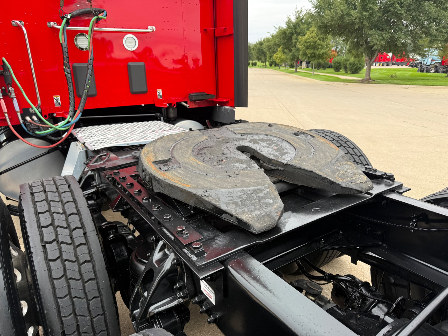 Kenworth T680 sleeper truck chassis showing fifth wheel hitch and rear cab area with hoses; red cab and connected components visible.