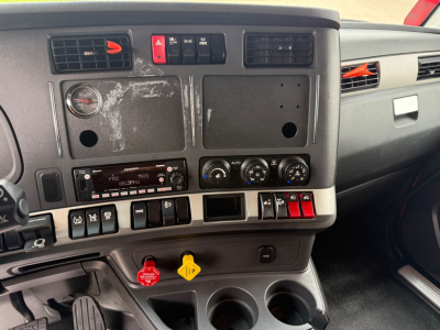 Cab interior dash cluster of a Kenworth T680 with multiple switches, gauges, and empty panels.